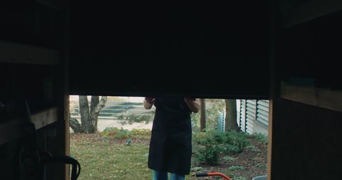 Senior mature Caucasian female closing the shed door. Shot on RED Cinema camera with 2x Anamorphic lens.