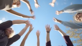 Bottom view of young diverse people putting their hands together outdoors. Friends with stack of hands showing unity and teamwork. Students standing in circle putting hands together - Powered by Shutterstock - Get 15% off with code: PIKWIZARD15