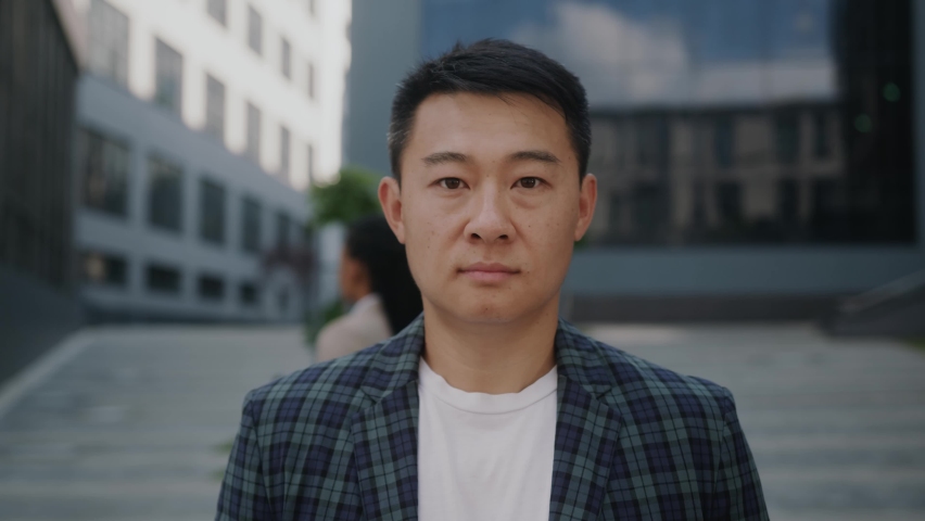 Portrait of handsome young asian businessman standing look at camera serious outside near business center. Successful career attractive manager handsome confident. Slow motion | Shutterstock HD Video #1059722354