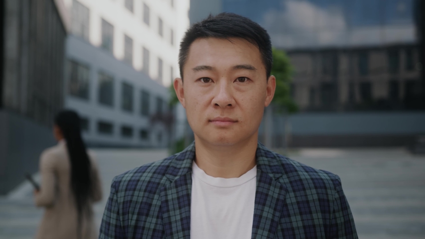 Portrait of handsome young asian businessman standing look at camera serious outside near business center. Successful career attractive manager handsome confident. Slow motion Royalty-Free Stock Footage #1059722354