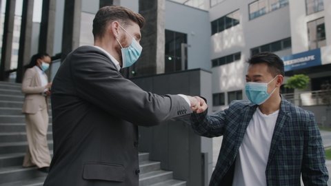 Two businessmen in medical mask meet each other and go to work together in modern office building. Quarantine successful respiratory protection manager coronavirus. Slow motion