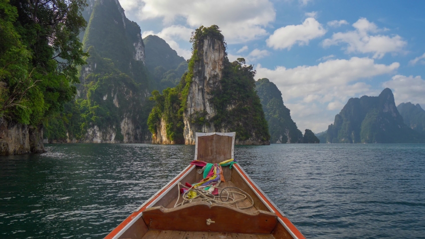 Boat trip on the lake Cheow Lan in Khao Sok National Park, Thailand. Famous "Three Sisters" karst formations rocks are seen in the distance. Magnificent nature of Thailand. HDR 4K shot Royalty-Free Stock Footage #1059722579
