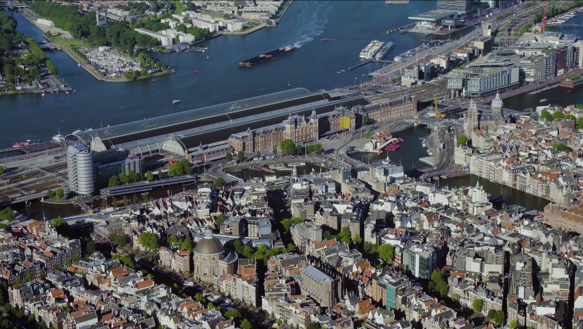 Aerial view of the famous Amsterdam Centraal Station, the largest railway station in Netherlands. Many ferries and cargo ships in the IJ. 