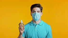 Man in protective mask applies disinfectant antiseptic to his hands and then shows - it is clean and sterile. Stop virus concept, bacteria protection.