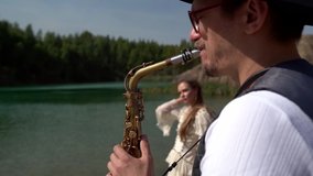 saxophonist and young woman on shore of picturesque lake in forest at summer day, romantic atmosphere - Powered by Shutterstock - Get 15% off with code: PIKWIZARD15