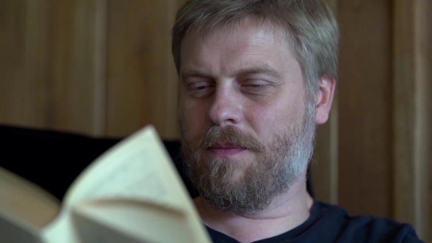 Middle-aged bearded man is reading book at home, closeup of face | Shutterstock HD Video #1059731138