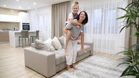 Happy family loving young mother playing piggyback with preteen daughter at home in living room, slow motion - Powered by Shutterstock - Get 15% off with code: PIKWIZARD15