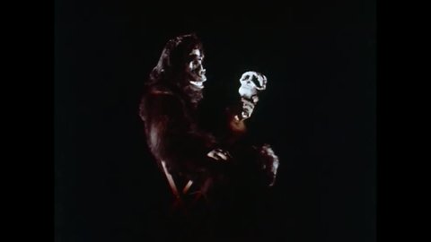 CIRCA 1965 - In this horror comedy, a man in a gorilla suit plays with a human skull.