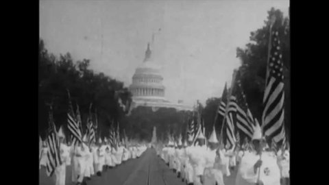 CIRCA 1920s - Members of the Ku Klux Klan, wearing glory suits, parade, with American flags, crosses and a Klansman dressed as Uncle Sam. 1928.