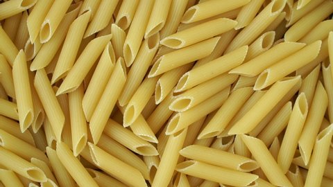 Top view of raw fresh pasta rotate on tray. Penne Rigate macaroni. Traditional Italian Cuisine. Durum wheat pasta. Food background. Close up