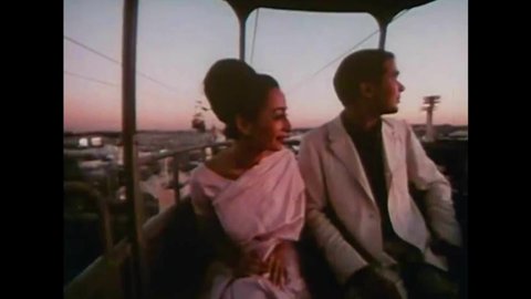 CIRCA 1960s - An Indian couple rides a sky tram at dusk at the 1964 New York World's Fair.