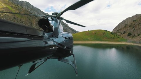 The helicopter takes off and flies over a mountain lake. View from the tail of the helicopter in 4K