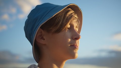 portrait of a happy boy in a hat looking at the beautiful blue sky, sun glare