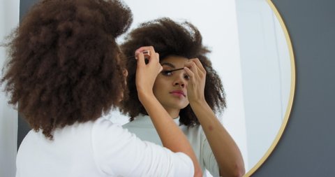 Young woman applying mascara in mirror / Claremont, Cape Town, South Africa