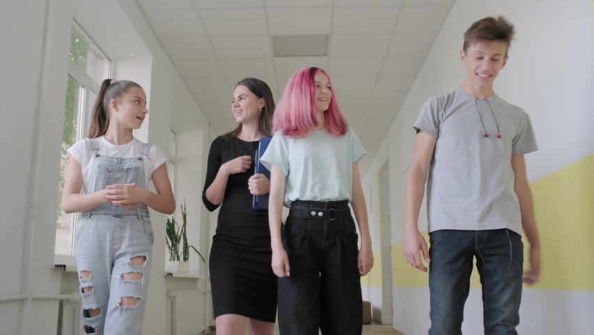 Young female teacher and student teenagers walking down the school hallway smiling and talking. Education, high school, adolescence concept. High quality 4k footage | Shutterstock HD Video #1059751199