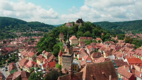 Smooth drone aerial circling of old church with castle on a hill in city of Sighisoara , Romania