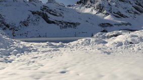 Low aerial footage of moving forward over the snowy shores of freezing lake Trübsee near Engelberg in Switzerland.