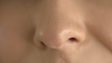 Extreme macro close up of a woman's nose while breathing in fresh air