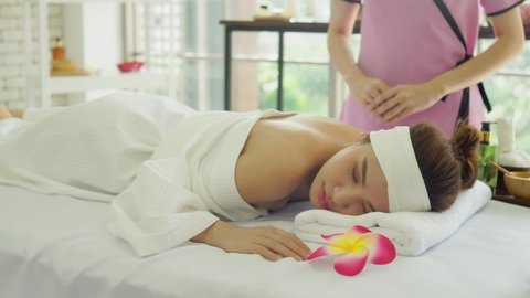 Relaxing beautiful Asian women lying in bed in spa salon. Young woman doing Thai massage. masseuse hand using herbal compresses to massage the woman shoulder and back. Massage and spa  for women ideas