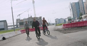 Extreme bmx guys bikers pedaling and jumping bunny hop tricks in sunny city street in summer. Cool young mtb boys riders have fun with bicycles. Urban outdoors lifestyle 4k raw video footage