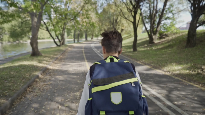 schoolgirl boy with a backpack run through the park home from school dream on a sunny day. Son little boy with a school backpack running home after school. concept education children learning