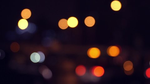 Blurred headlights of moving cars at crossroads of big night city. Abstract background traffic jam in defocus. Transport concept