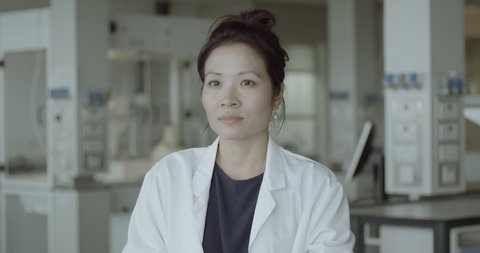 Portrait of Young Adult Female Chinese Doctor standing in science laboratory looking at camera wearing lab coat and stethoscope