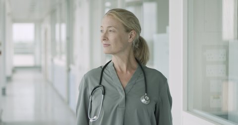 Portrait of confident Mature Female Doctor standing in hospital corridor looking at camera with stethoscope