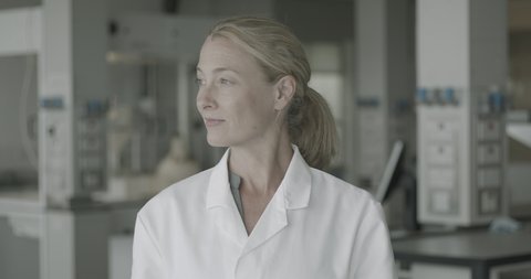 Portrait of confident mature female scientist standing science laboratory looking at camera wearing lab coat