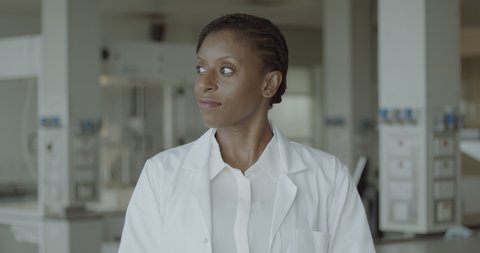 Portrait of confident female black doctor standing in hospital ward looking at camera wearing lab coat Video de stock