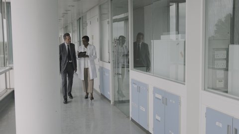 Doctors meeting in hospital corridor discussing test results on digital tablet computer technology