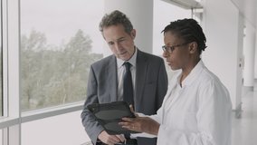 Doctors meeting in hospital corridor discussing test results on digital tablet computer technology - Powered by Shutterstock - Get 15% off with code: PIKWIZARD15