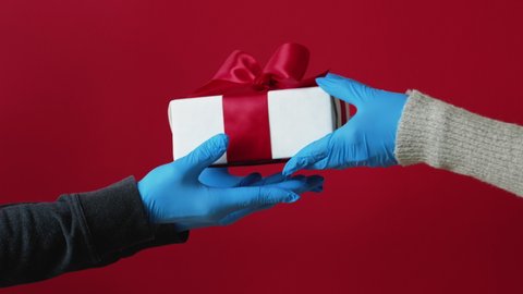 Pandemic Christmas hygiene. Gift delivery. COVID-19 New Year 2021. Quarantine measures. Hands in blue protective gloves receiving wrapped present in box isolated on red background loop set of 8. Stock Video