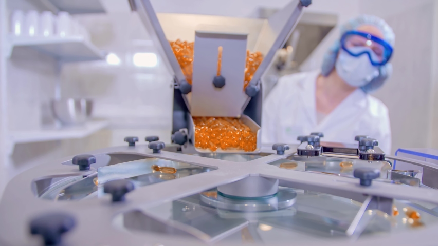 Slow motion of a female lab worker pouring orange pills into a bottling machine Royalty-Free Stock Footage #1059783824