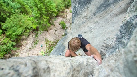 Young boy climbs rocky mountain wall in Burjakove Peci. Slovenia