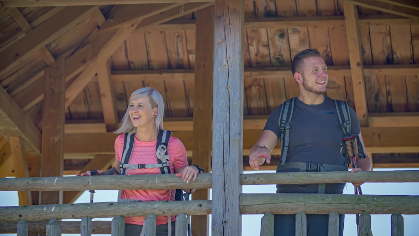 A young couple of travellers smiling and appreciating the sight from a viewpoint. Slow motion