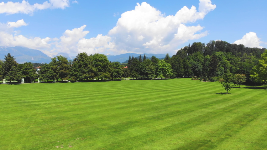Medium Wide angle Dolly in Drone Shot of well maintained lawn and surrounding trees in Volcji Potok Arboretum during the day
