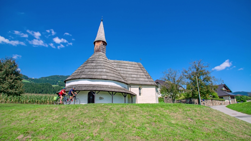 Couple cyclist passing by the unique Romanesque church Saint John the Baptist