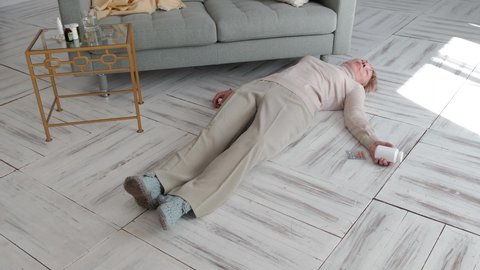 An elderly woman lies unconscious on the floor of a house