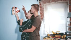 Young couple choosing paint color from samples for new home interior design. Side view of happy man and woman in love doing home renovation choosing wall color and kissing - Powered by Shutterstock - Get 15% off with code: PIKWIZARD15