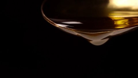 Drop of olive oil drips from the spoon.
