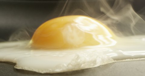 Closeup of Cracked Egg Sizzling on a Frying Pan Shot on Red Camera.
