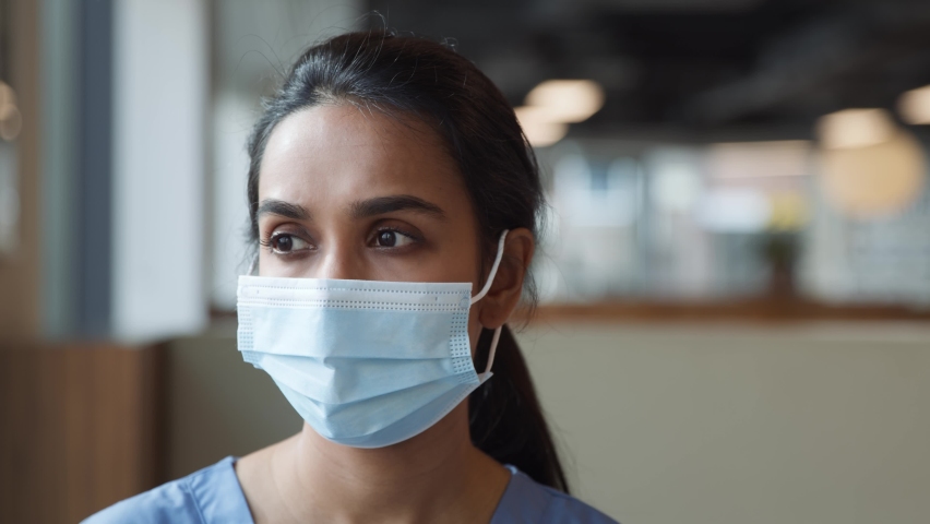 Portrait of smiling overworked nurse in scrubs taking off face mask during break in busy hospital during health pandemic - shot in slow motion Royalty-Free Stock Footage #1059802034