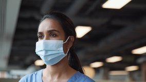 Portrait of smiling overworked nurse in scrubs taking off face mask during break in busy hospital during health pandemic - shot in slow motion - Powered by Shutterstock - Get 15% off with code: PIKWIZARD15