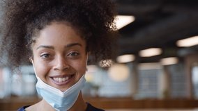 Portrait of smiling overworked nurse in scrubs taking off face mask during break in busy hospital during health pandemic - shot in slow motion - Powered by Shutterstock - Get 15% off with code: PIKWIZARD15