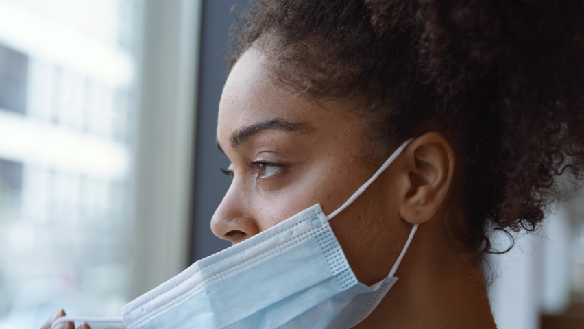 Portrait of overworked nurse in scrubs putting on face mask taking break and looking out of window in busy hospital during health pandemic - shot in slow motion Royalty-Free Stock Footage #1059802055