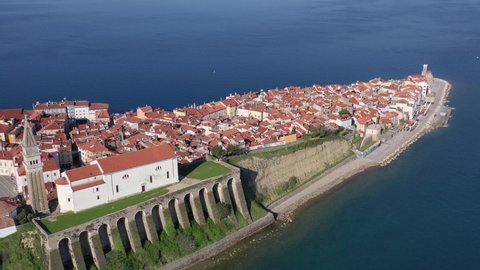 High aerial pull back drone view of parish of Piran and coastal village of red roofs, Slovenia