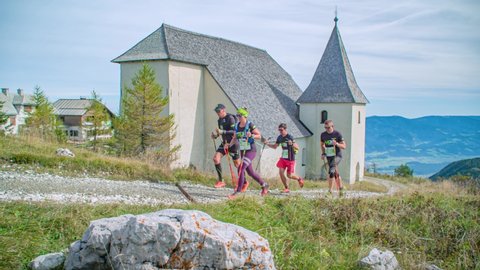 Urslja gora / Slovenia - 04 19 2020: marathon runners making the way of 24k ultra trail near a church, Alps 