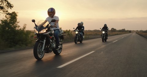 A group of bikers travel on motorcycles, ride on the highway in the evening before sunset