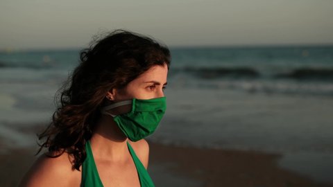 Woman in beach quits her face surgical mask and breathe, then stick out her tongue